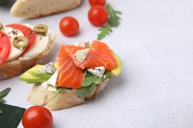 Photo of Different tasty bruschettas and ingredients on light grey textured table, space for text