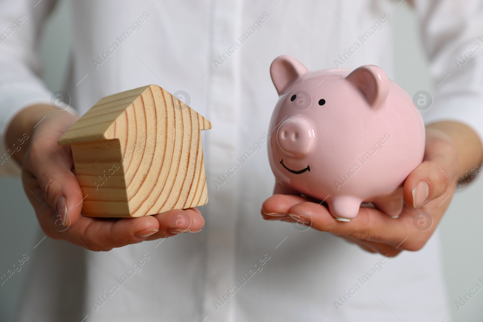 Photo of Woman holding piggy bank and house model on white background, closeup