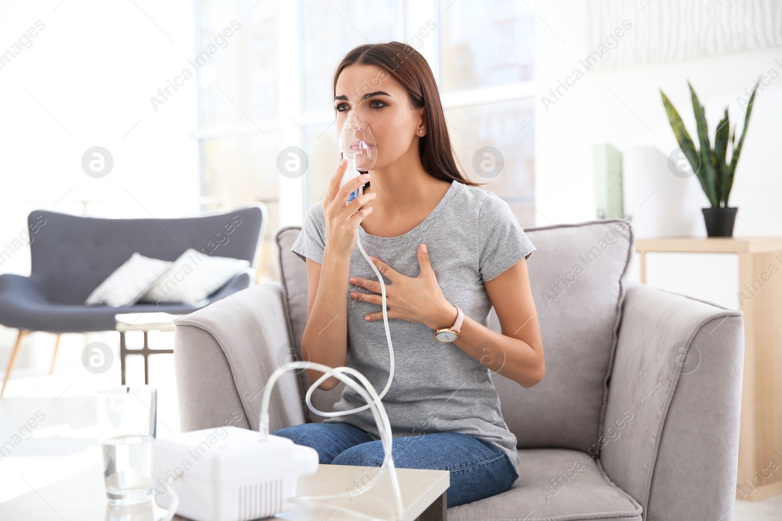 Photo of Young woman with asthma machine in light room