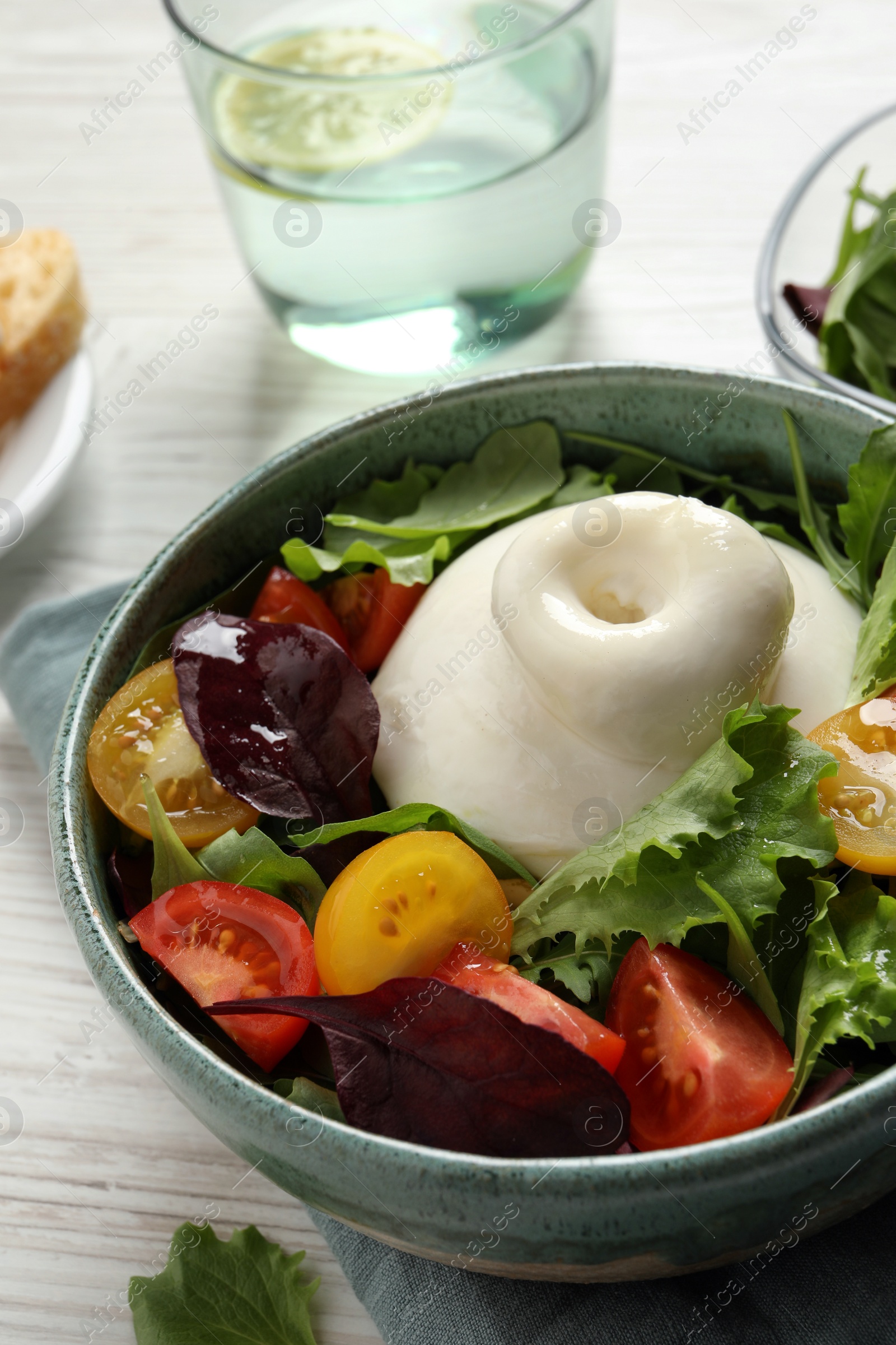 Photo of Delicious burrata salad with colorful cherry tomatoes and arugula on white wooden table, closeup