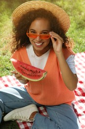 Photo of Beautiful young African American woman with slice of watermelon on green grass