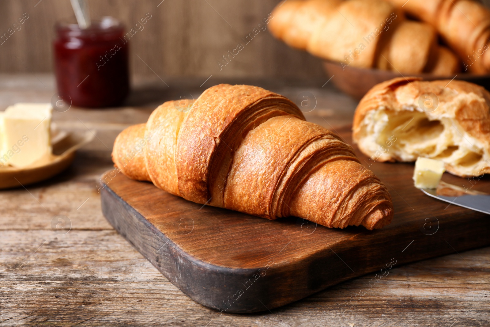 Photo of Tasty fresh croissants on wooden table, closeup