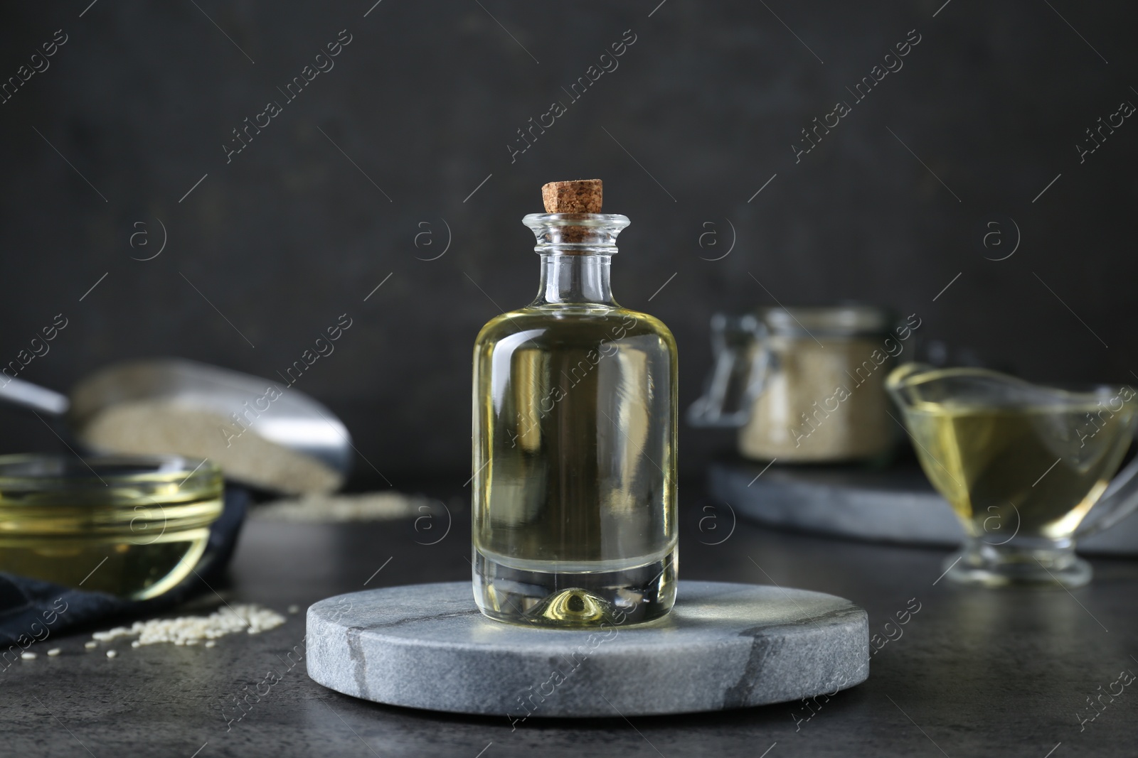 Photo of Sesame oil in glass bottle on dark grey table
