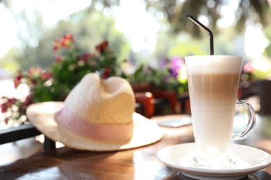 Photo of Glass cup of coffee on table in outdoor cafe, space for text