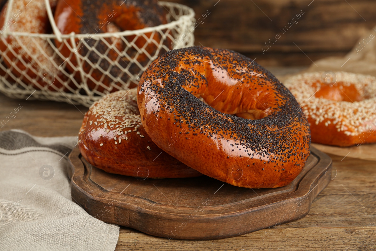 Photo of Delicious fresh bagels with poppy and sesame seeds on wooden table