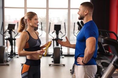 Trainer having discussion with woman in gym