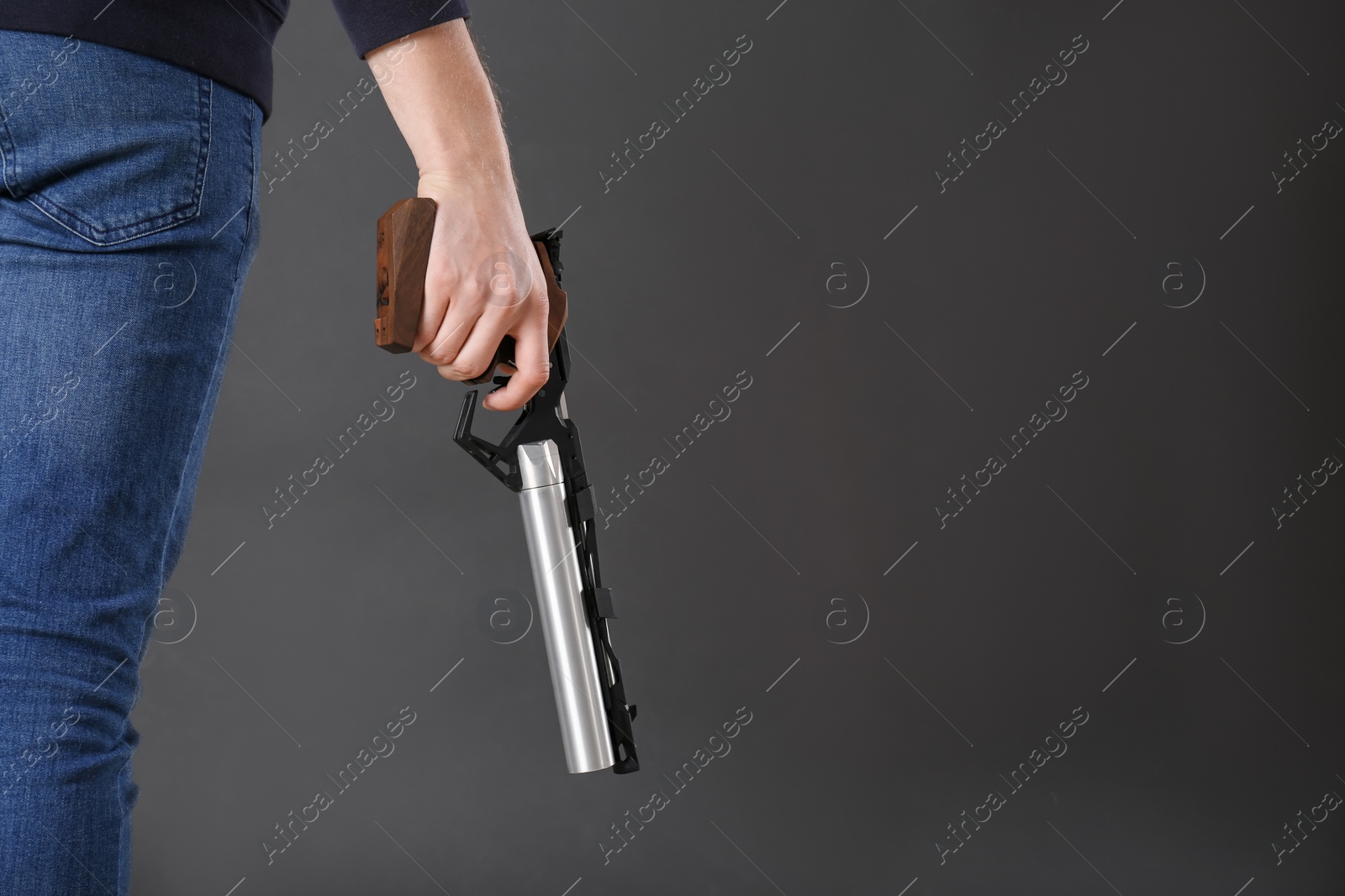 Photo of Gun shooting sport. Man holding standard pistol on dark background, closeup. space for text