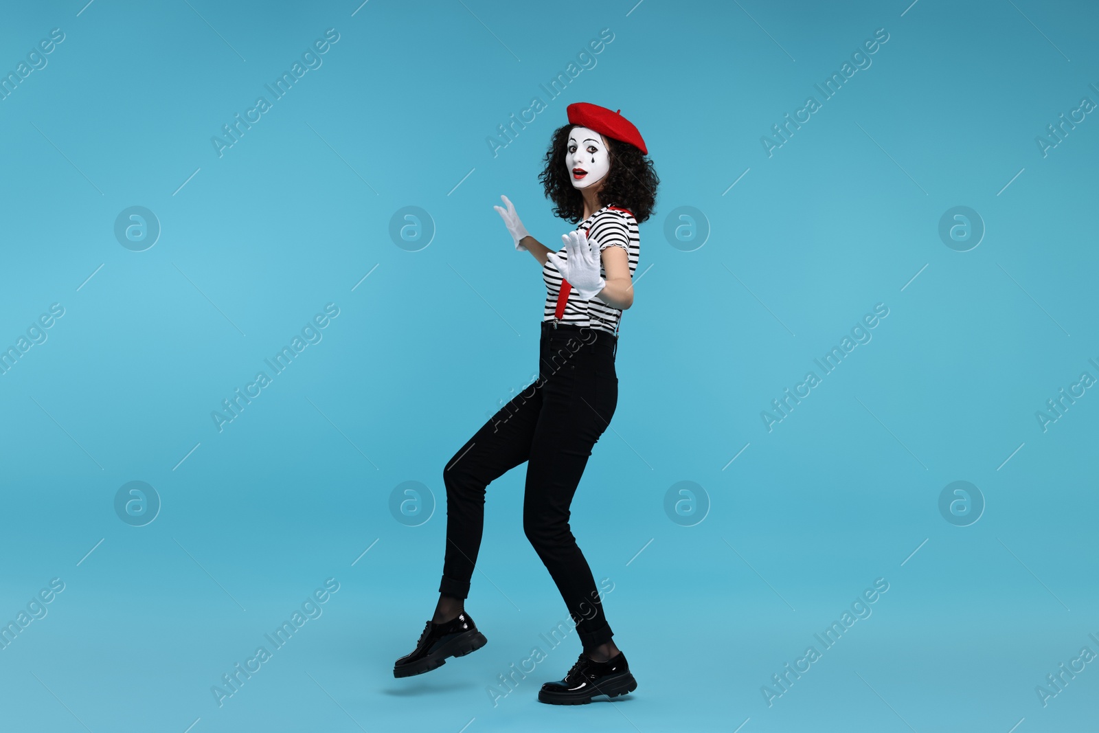 Photo of Funny mime with beret posing on light blue background