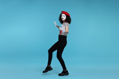 Photo of Funny mime with beret posing on light blue background