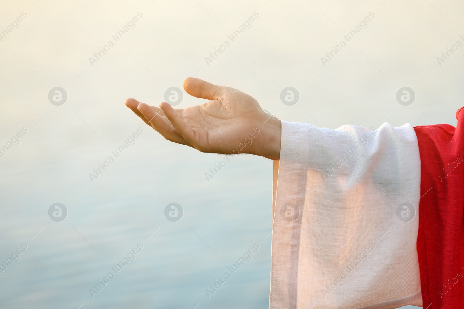 Photo of Jesus Christ reaching out his hand near water outdoors, closeup