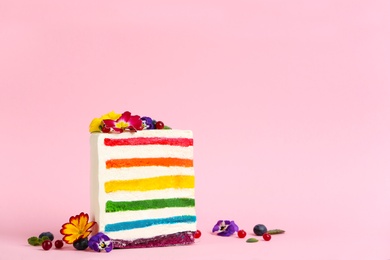 Photo of Slice of delicious rainbow cake with flowers on color background