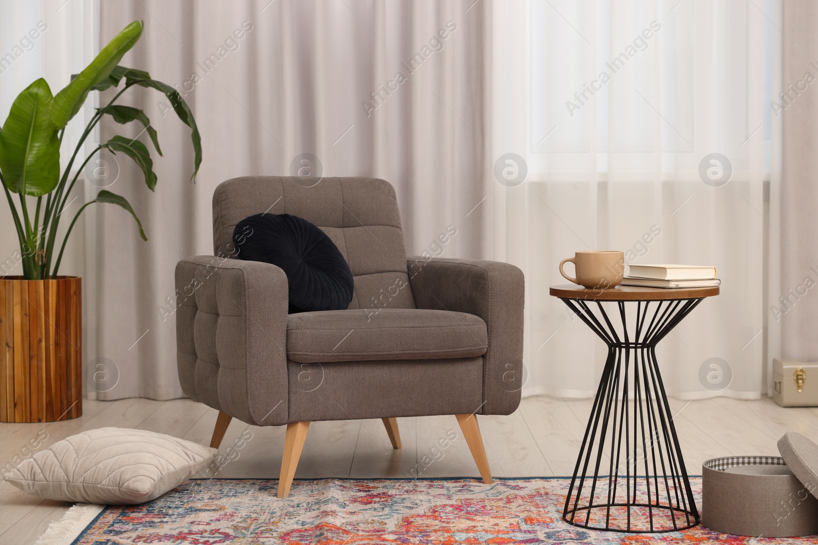 Photo of Stylish gray armchair and small table in living room. Interior design