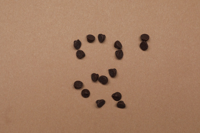 Delicious chocolate chips on brown background, top view