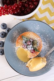 Photo of Tasty vanilla fondant with white chocolate and berries on light wooden table, flat lay