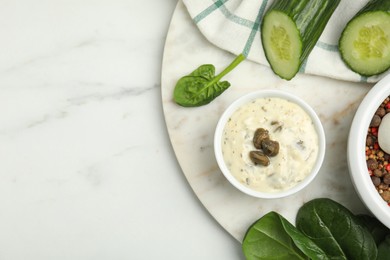 Photo of Creamy caper sauce in bowl and ingredients on white marble table, flat lay. Space for text
