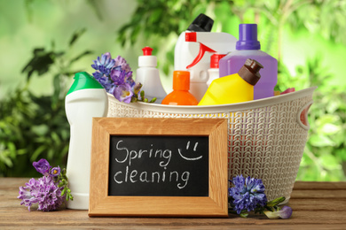 Photo of Composition with Spring Cleaning sign, flowers and detergents on wooden table