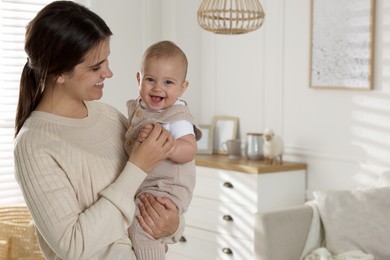 Photo of Happy young mother with her baby in living room. Space for text