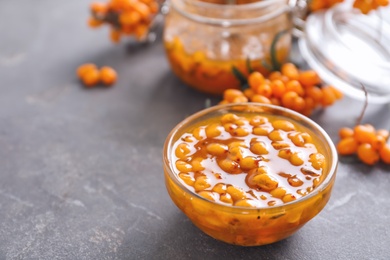 Delicious sea buckthorn jam and fresh berries on grey table. Space for text