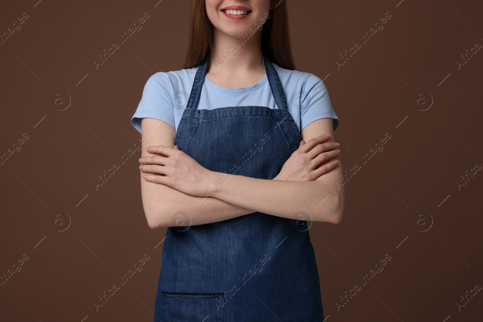 Photo of Woman wearing kitchen apron on brown background, closeup. Mockup for design