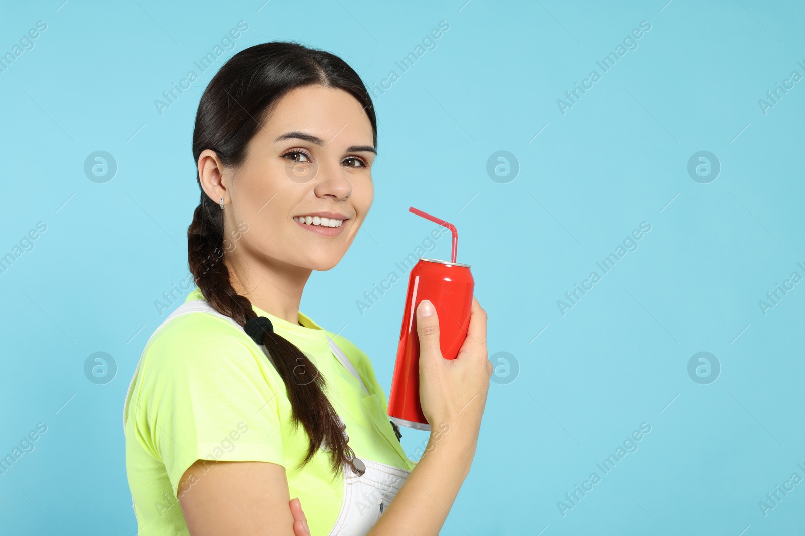 Photo of Beautiful happy woman holding red beverage can on light blue background. Space for text