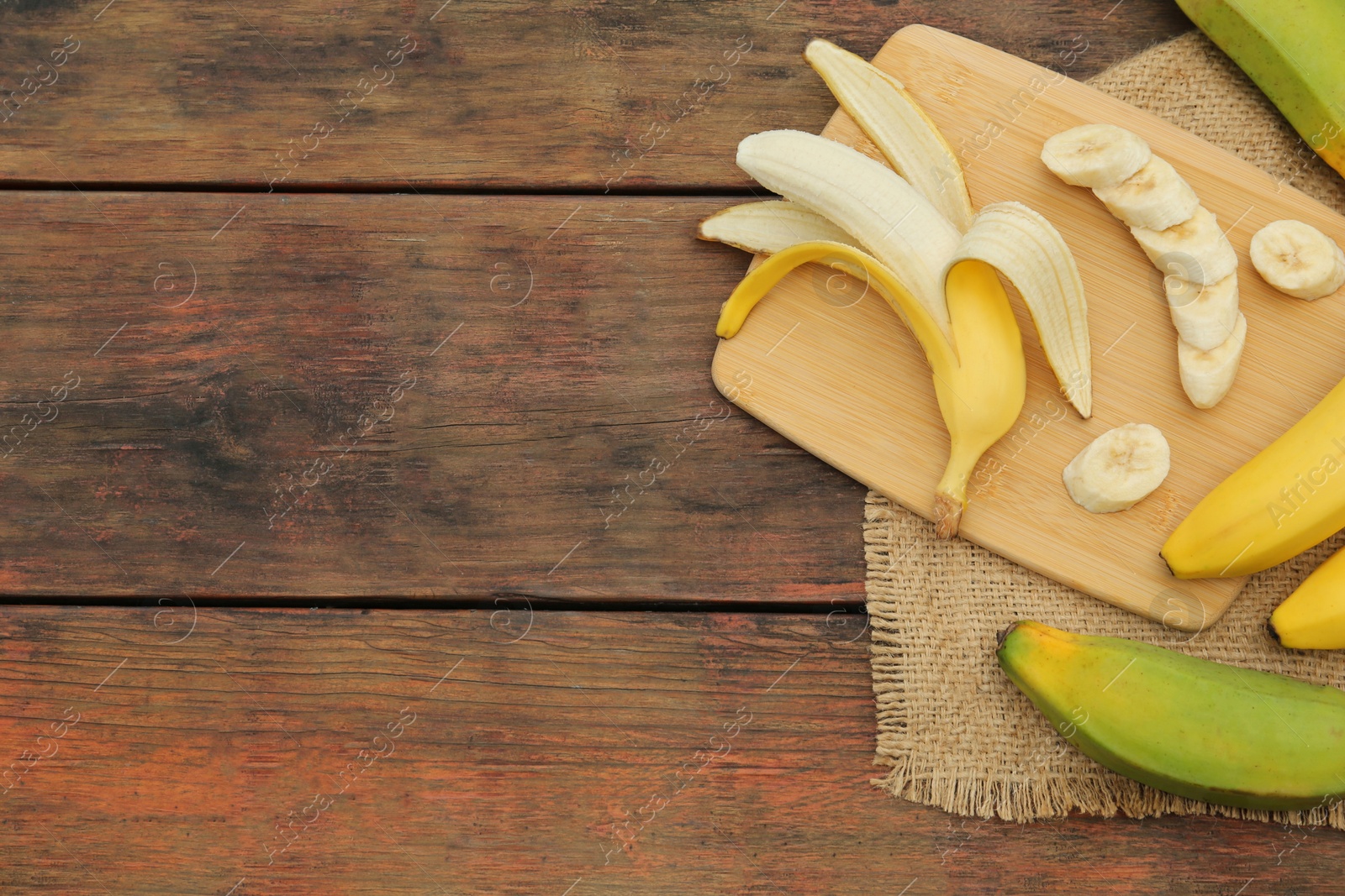 Photo of Whole and cut bananas on wooden table, flat lay. Space for text