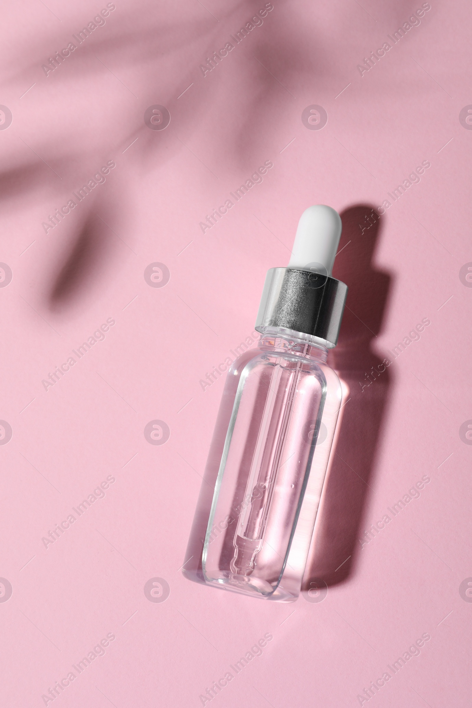 Photo of Bottle of cosmetic oil on pink background, top view