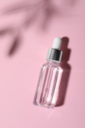 Bottle of cosmetic oil on pink background, top view