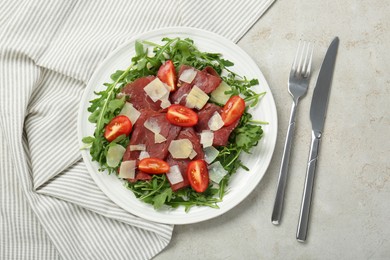 Delicious bresaola salad with parmesan cheese served on light grey textured table, flat lay