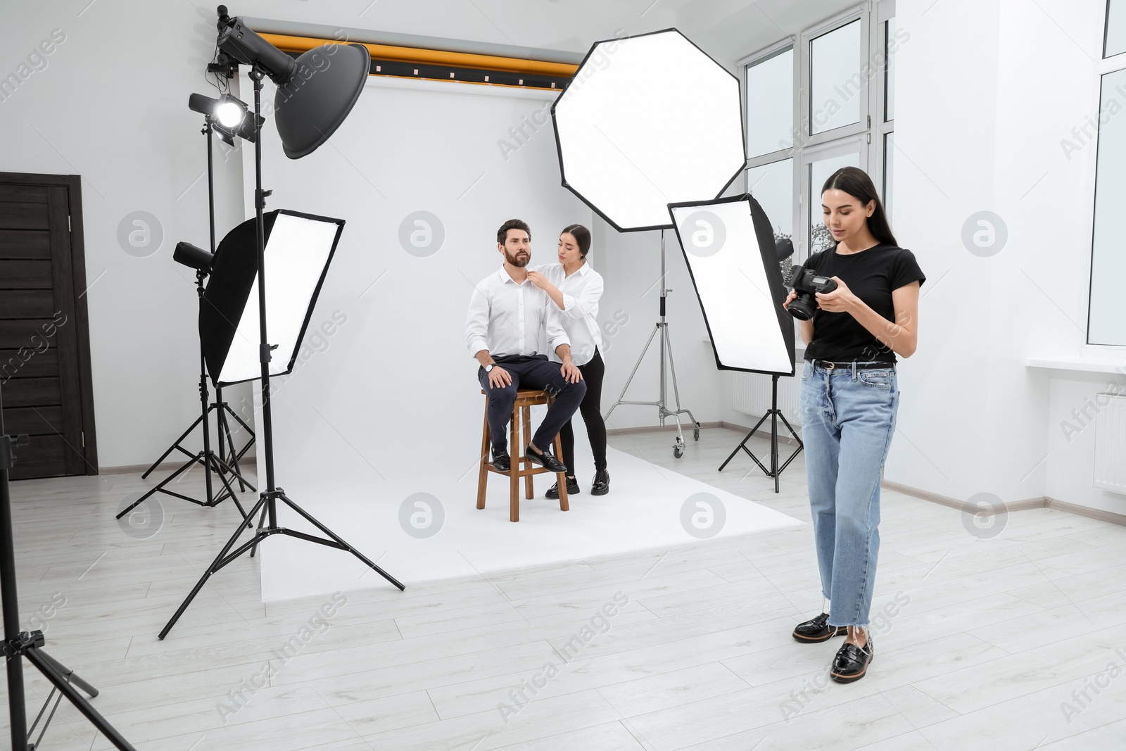 Photo of Professional photographer and stylist working with model in modern photo studio