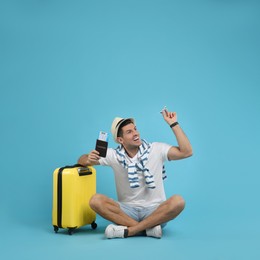 Photo of Male tourist holding passport with ticket and toy airplane near suitcase on turquoise background, space for text