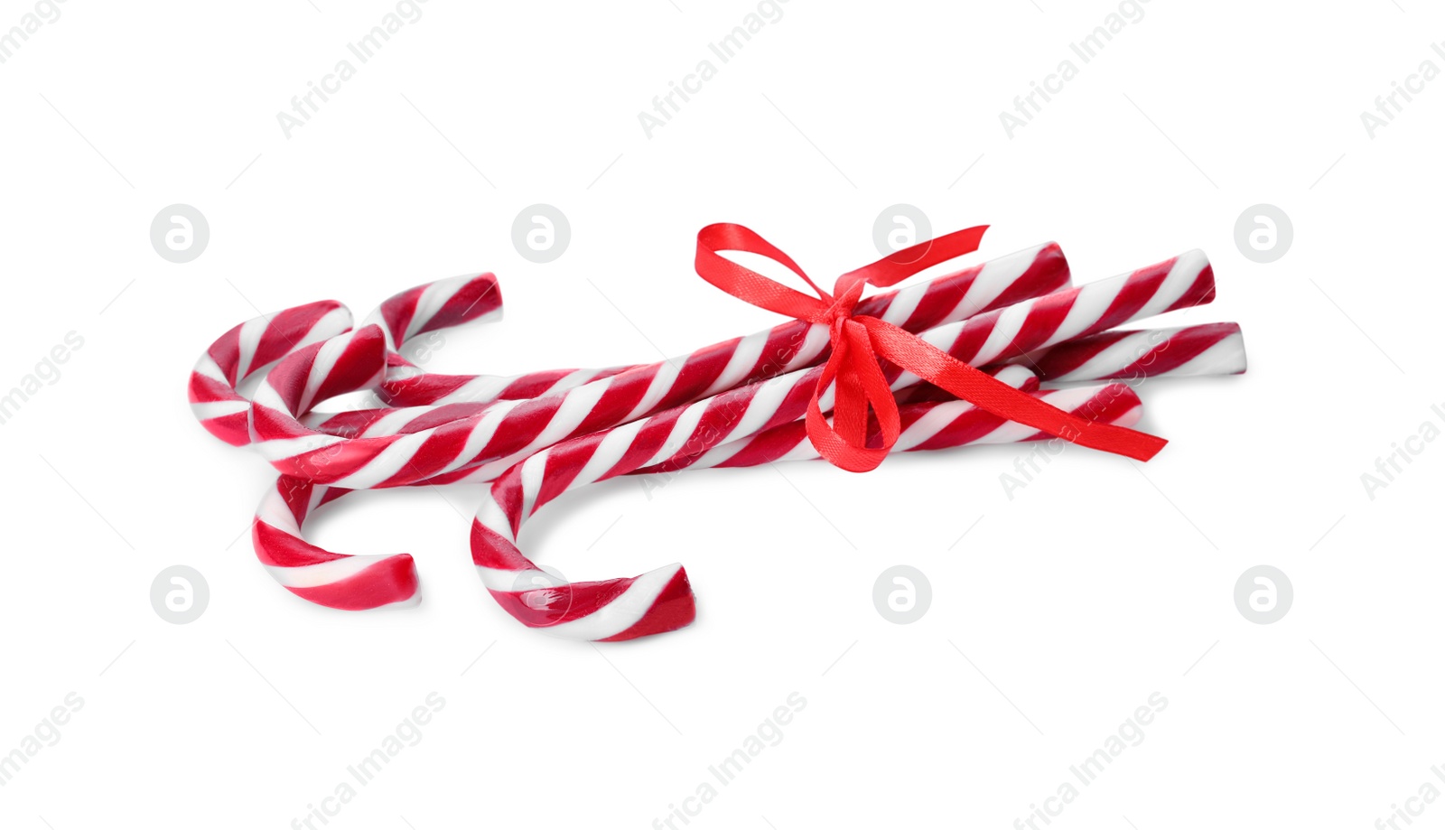 Photo of Sweet Christmas candy canes with red bow on white background