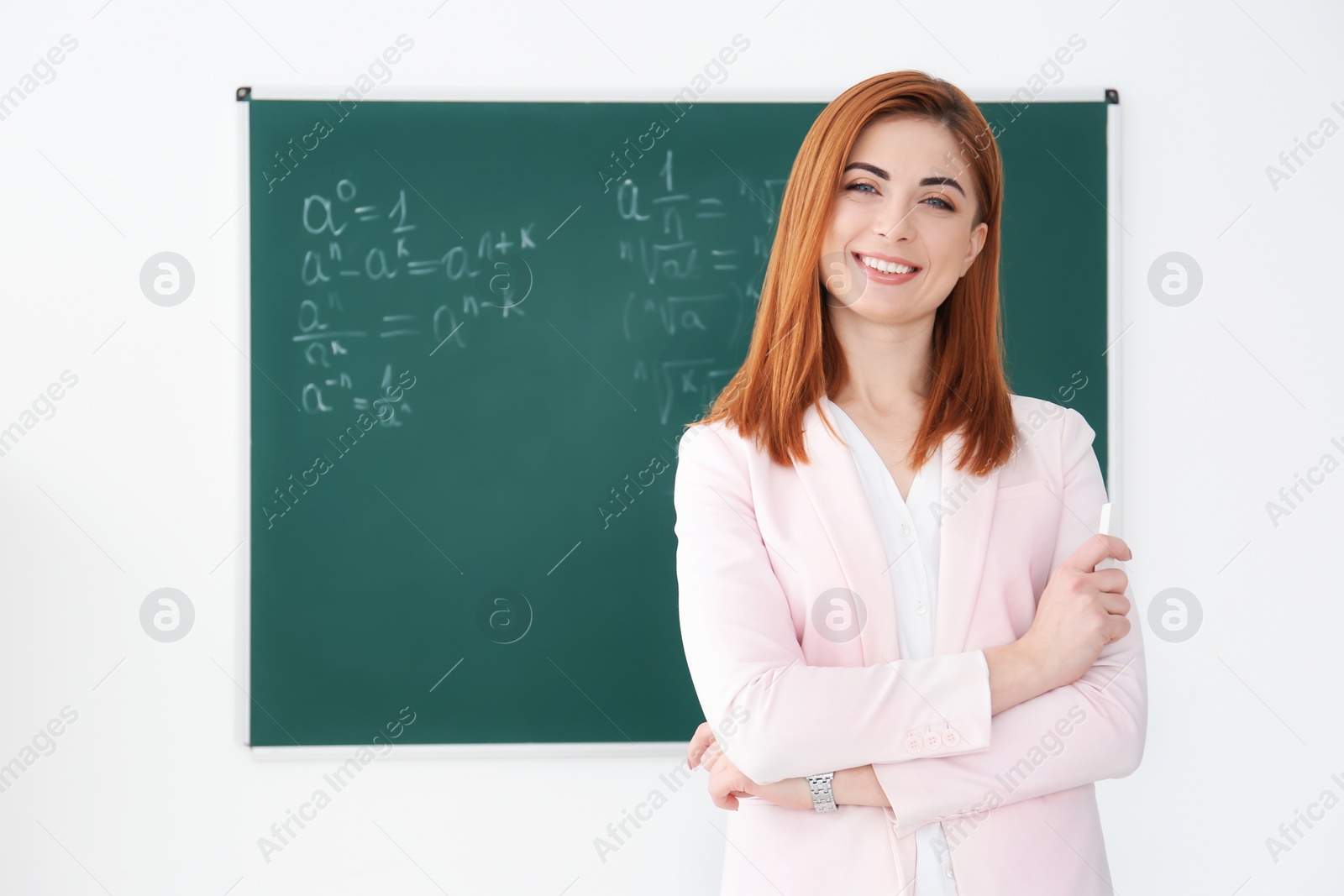 Photo of Beautiful young teacher near blackboard in classroom