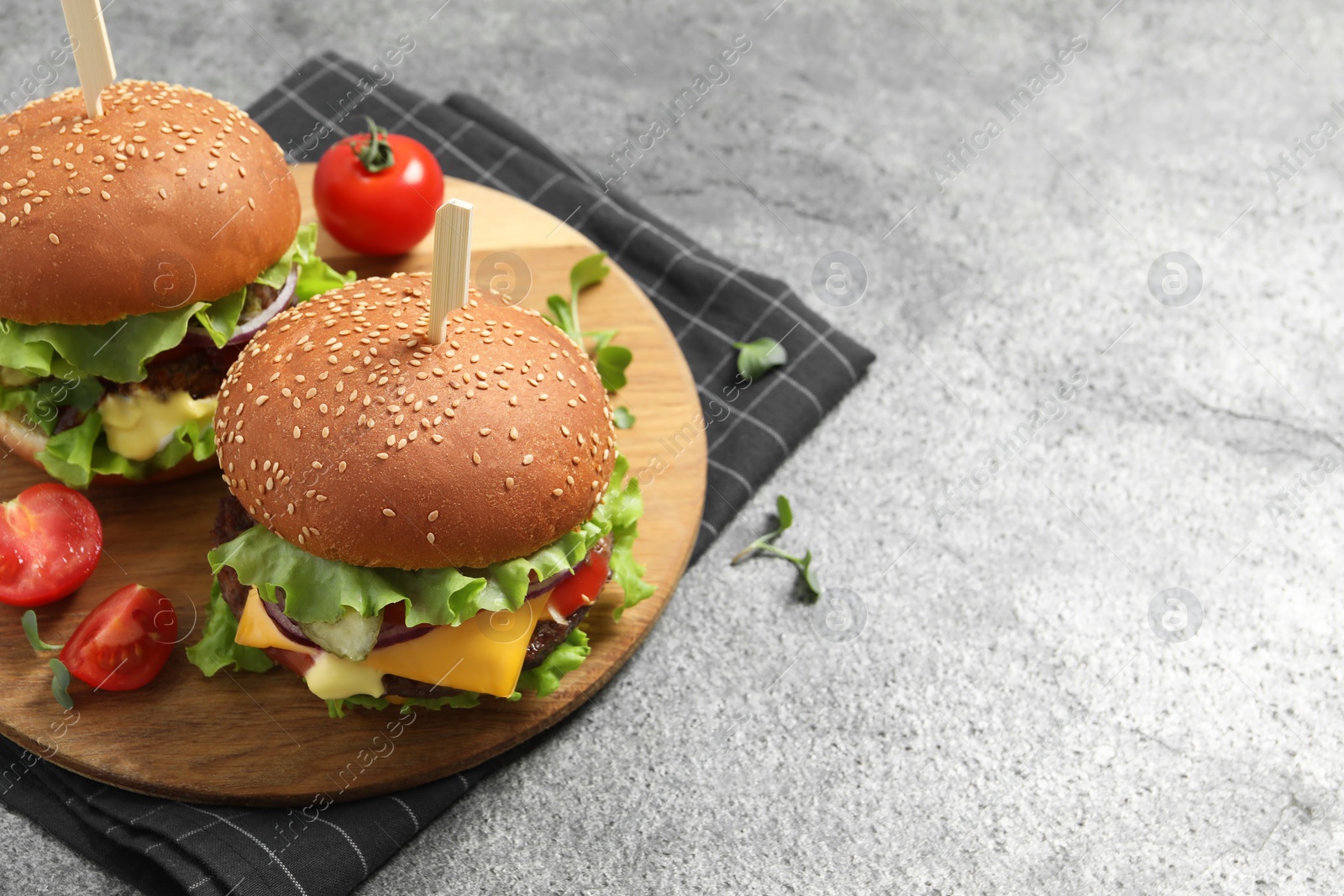 Photo of Delicious burgers with beef patty and tomatoes on grey table. Space for text