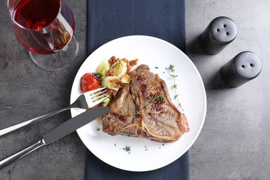 Delicious fried beef meat and vegetables served on grey table, flat lay