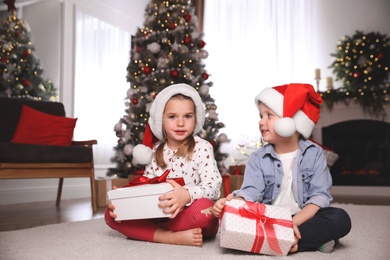 Photo of Cute little children with Christmas gifts on floor at home