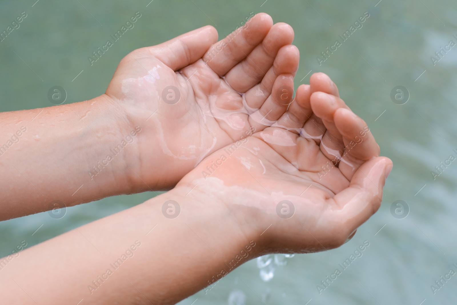 Photo of Kid holding water in hands above sea outdoors, closeup