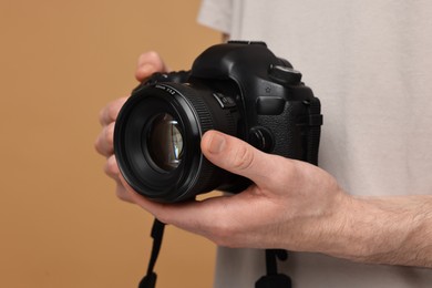 Photo of Photographer holding camera on beige background, closeup