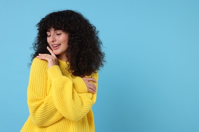 Photo of Happy young woman in stylish yellow sweater on light blue background, space for text