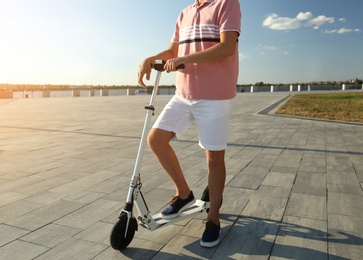 Photo of Man with modern kick scooter on waterfront, closeup