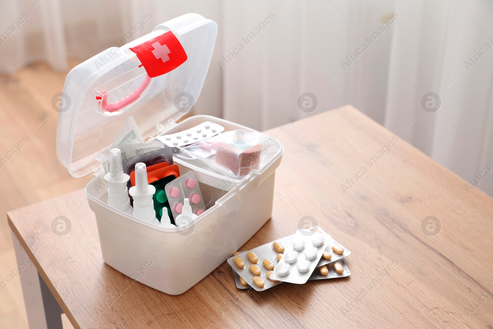 Photo of First aid kit and medicaments on wooden table indoors, space for text