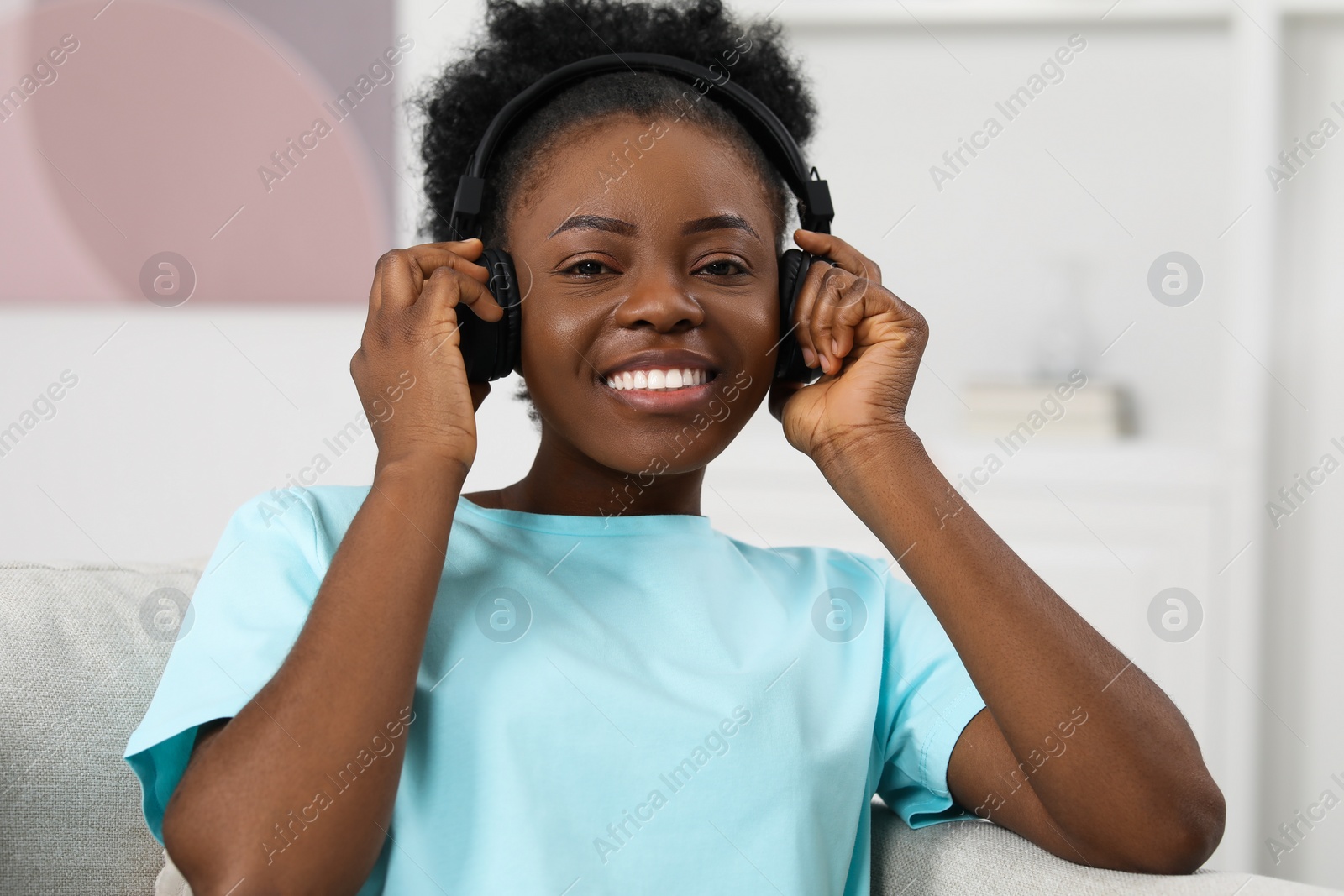 Photo of Beautiful young woman in headphones enjoying music on sofa indoors