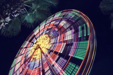 Photo of Beautiful glowing Ferris wheel against dark sky, low angle view