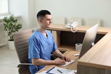 Photo of Smiling medical assistant working with computer at hospital reception
