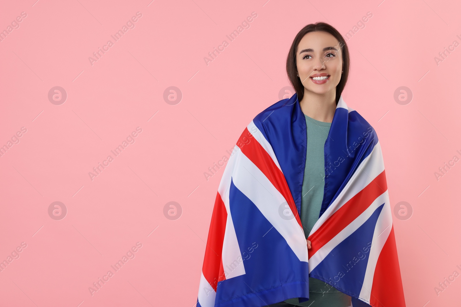 Photo of Young woman with flag of United Kingdom on pink background, space for text