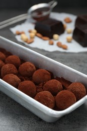 Delicious chocolate candies powdered with cocoa on grey table, closeup