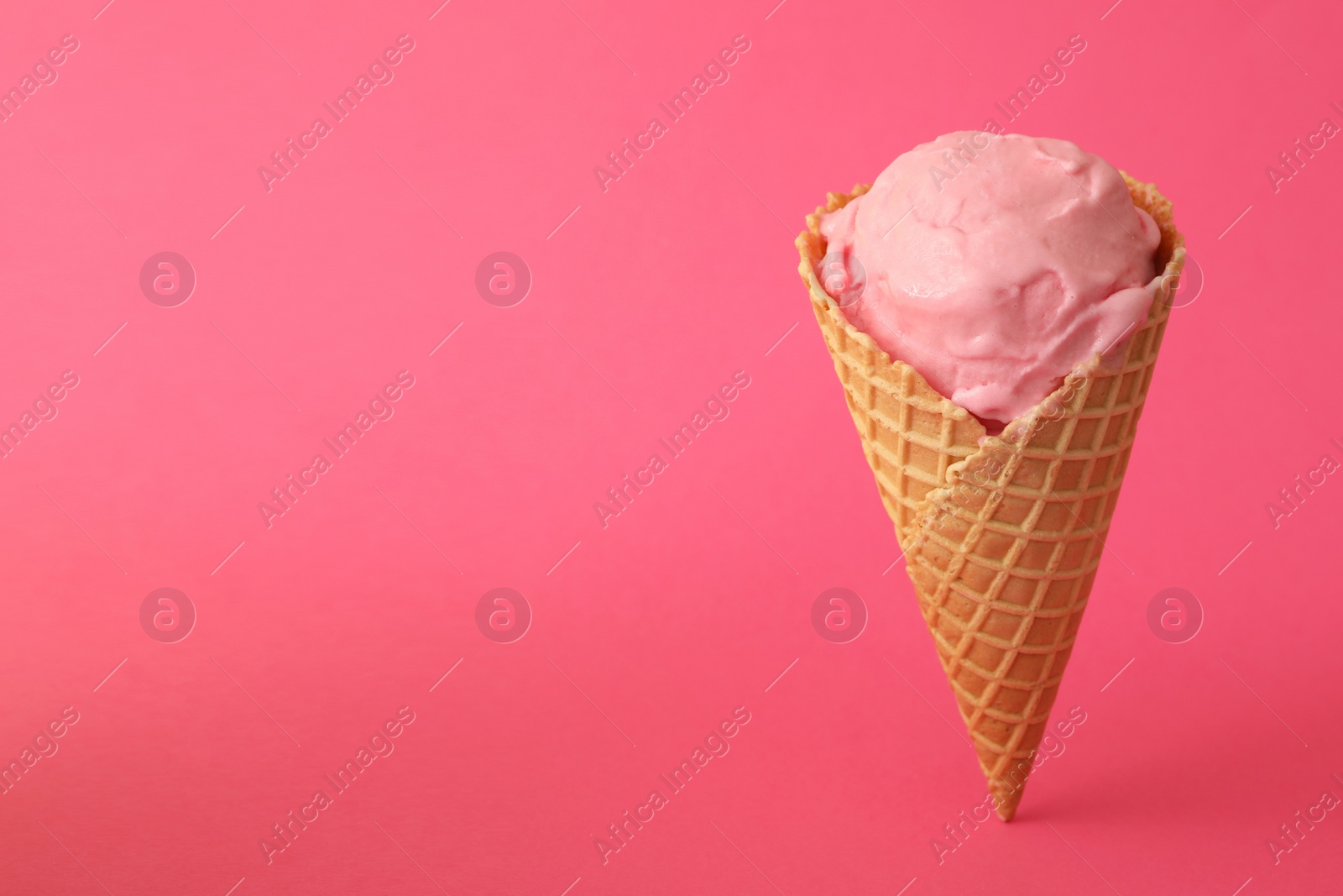 Photo of Delicious ice cream in waffle cone on pink background. Space for text