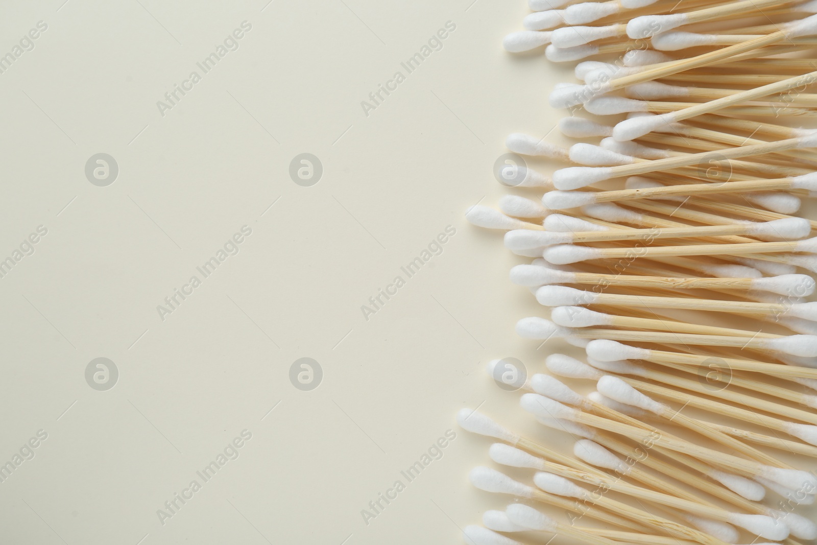 Photo of Many wooden cotton buds on beige background, flat lay. Space for text