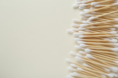 Photo of Many wooden cotton buds on beige background, flat lay. Space for text