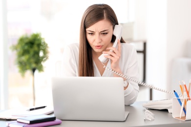 Young woman talking on phone at workplace