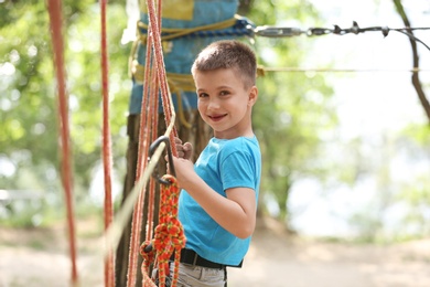 Photo of Little boy climbing in adventure park. Summer camp